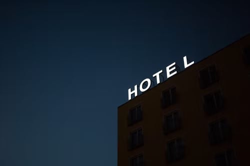 La parte superior de un hotel, enfocando el letrero que dice Hotel en color blanco en la noche